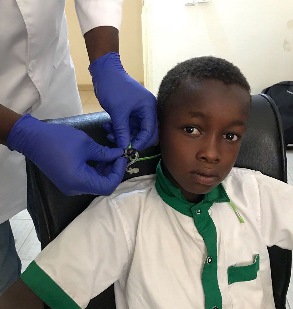 A young boy is fitted with a hearing aid.